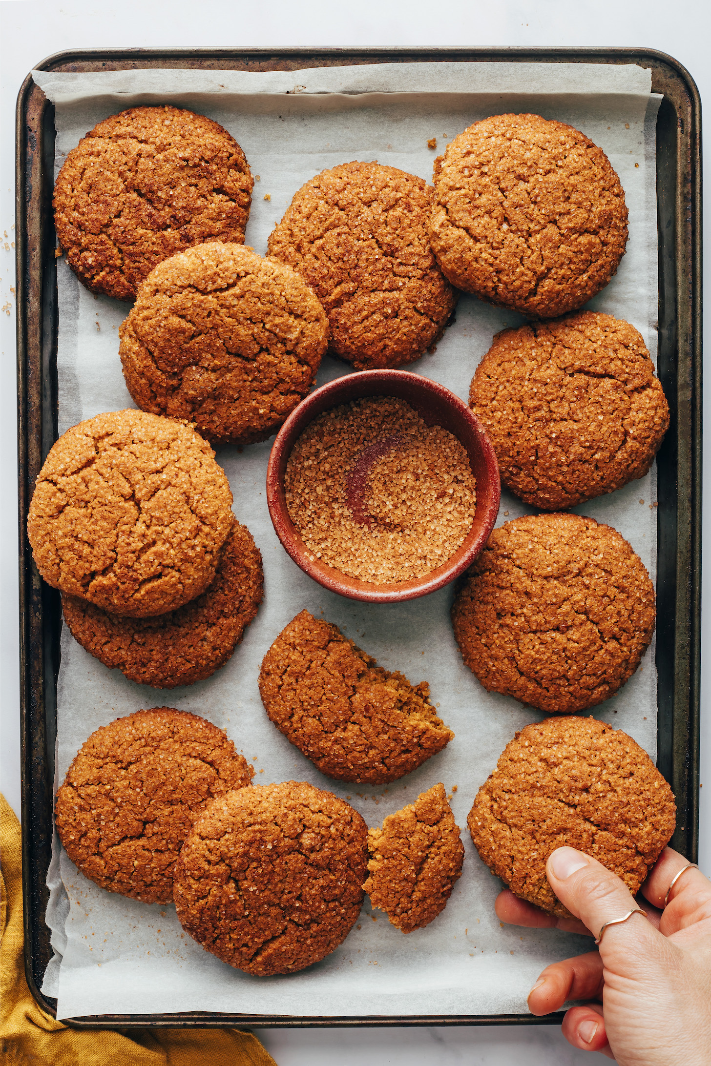 Baking sheet of vegan gluten-free pumpkin snickerdoodles next to a bowl of pumpkin spice sugar