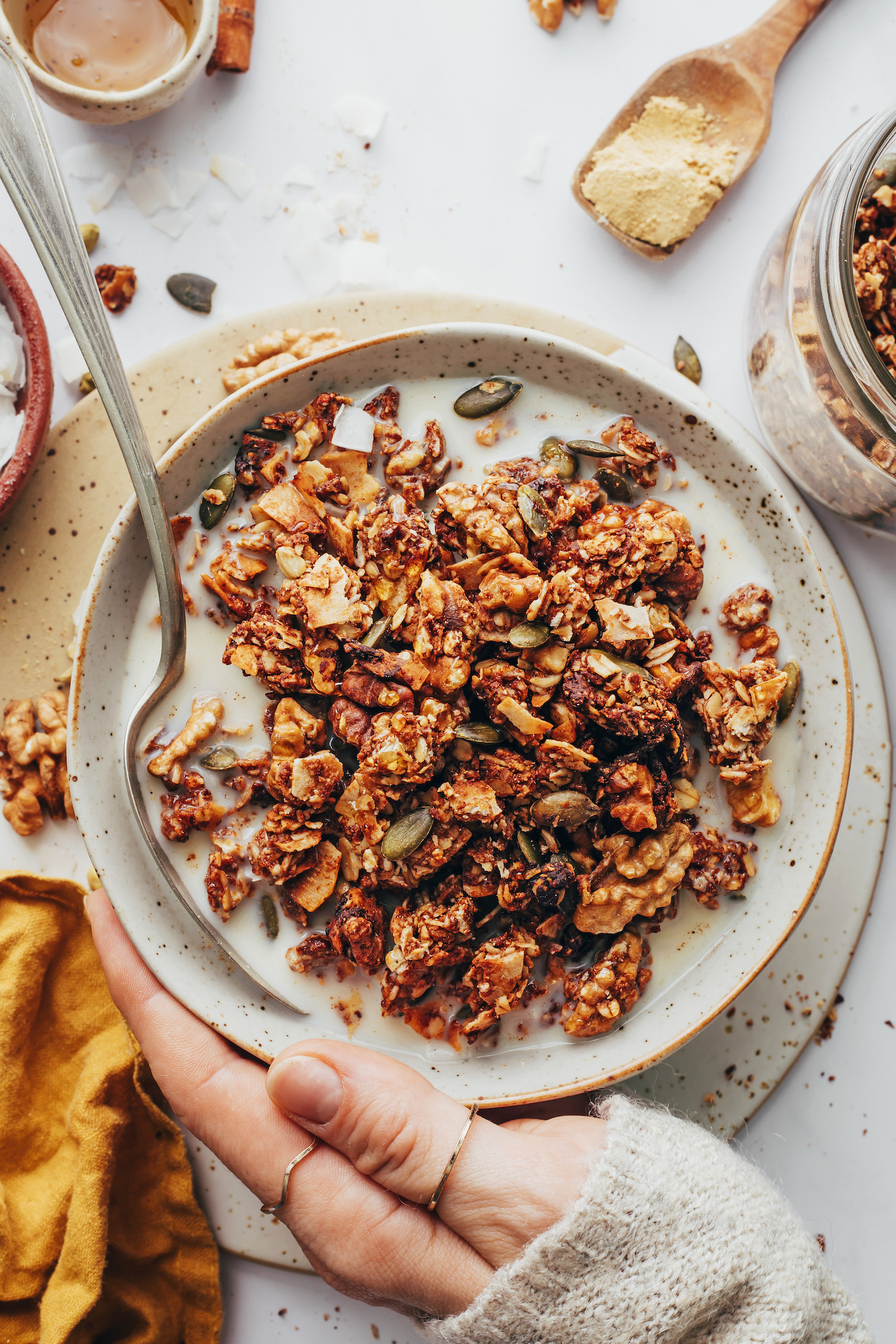 Hand holding a bowl of chai granola with almond milk
