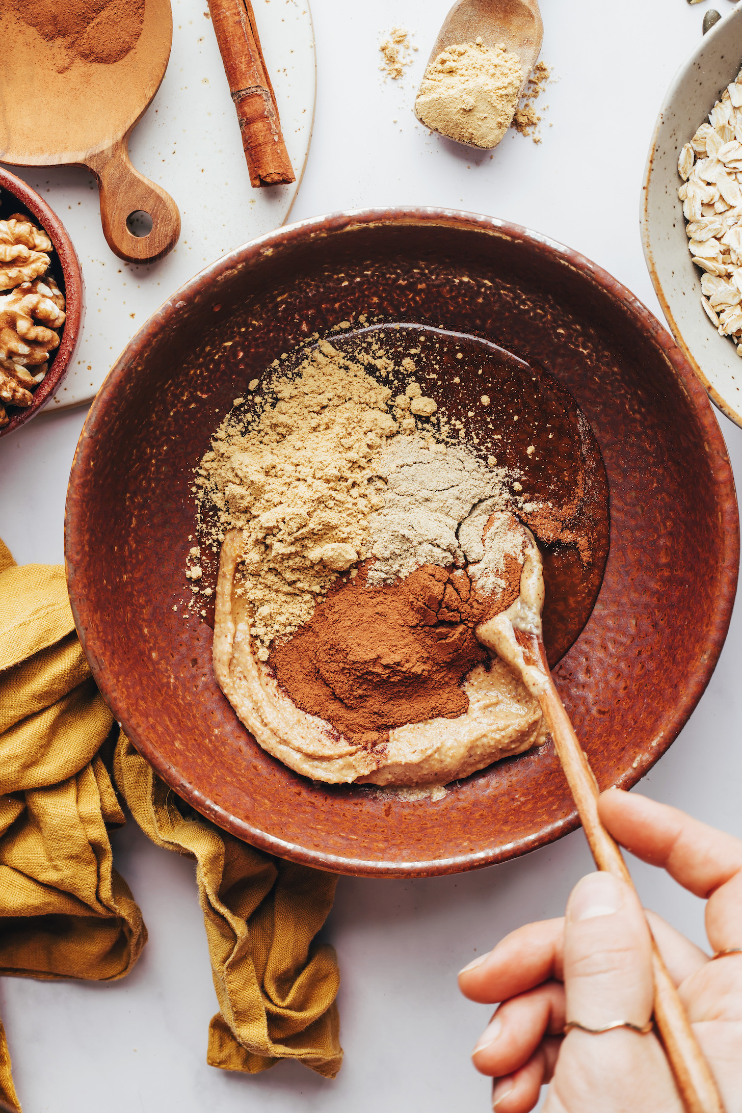 Stirring cinnamon ginger, cardamom, almond butter, and maple syrup in a bowl