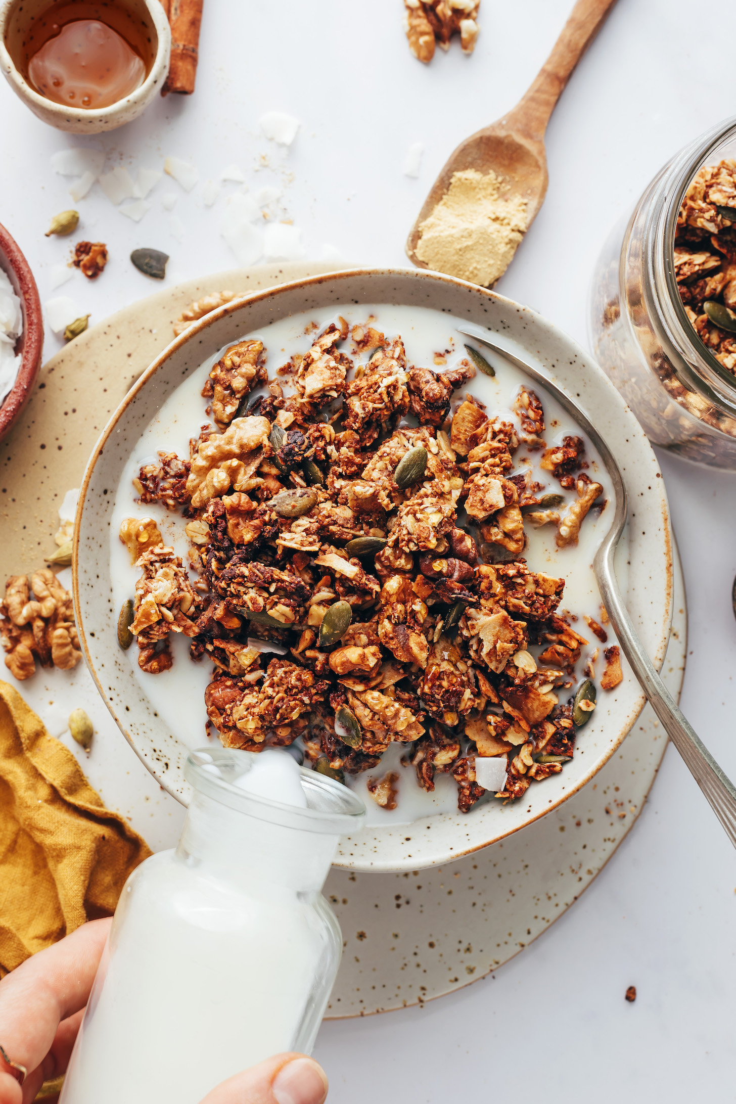 Pouring dairy-free milk into a bowl of chai-spiced granola
