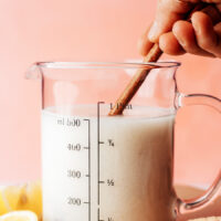 Stirring almond milk and lemon juice in a measuring glass to make vegan buttermilk