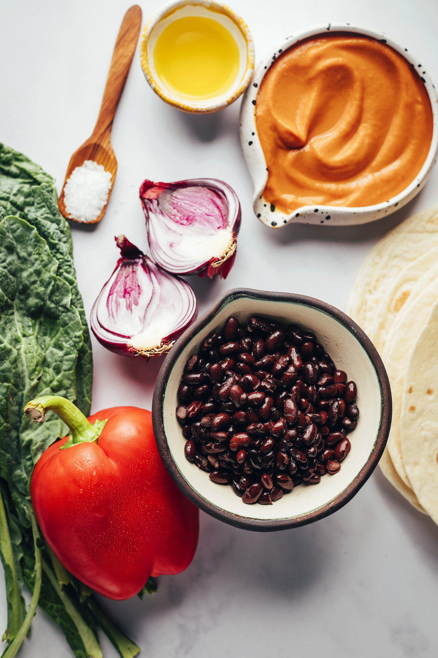 Pumpkin enchilada sauce, tortillas, black beans, red bell pepper, kale, red onion, salt, and olive oil