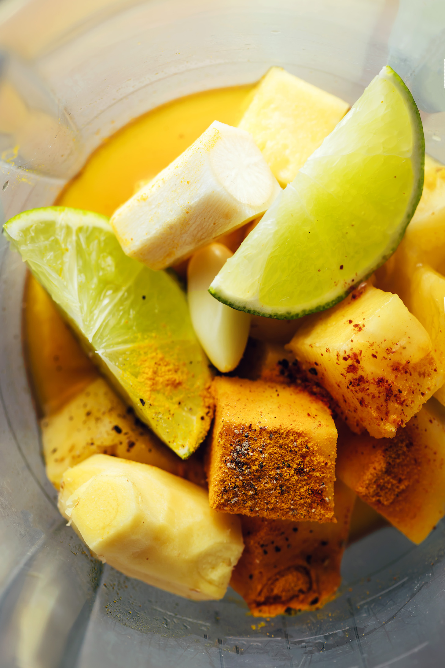 Blender with apple cider vinegar, lime wedges, horseradish, ginger, garlic, and pineapple