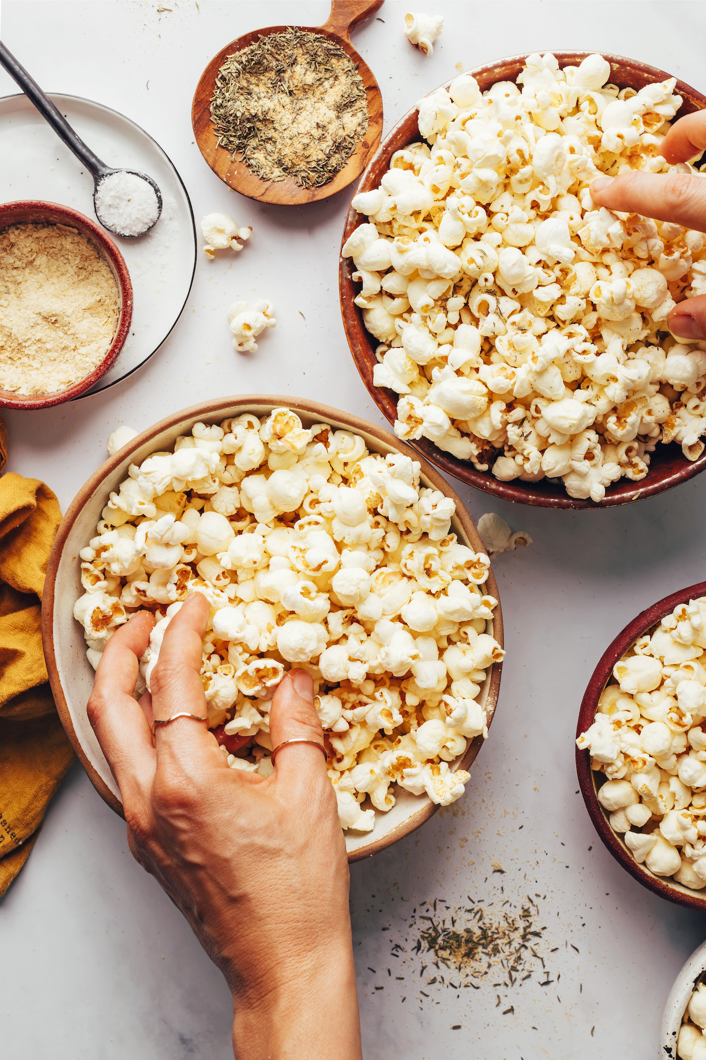 Hands reaching in to pick up popcorn from bowls