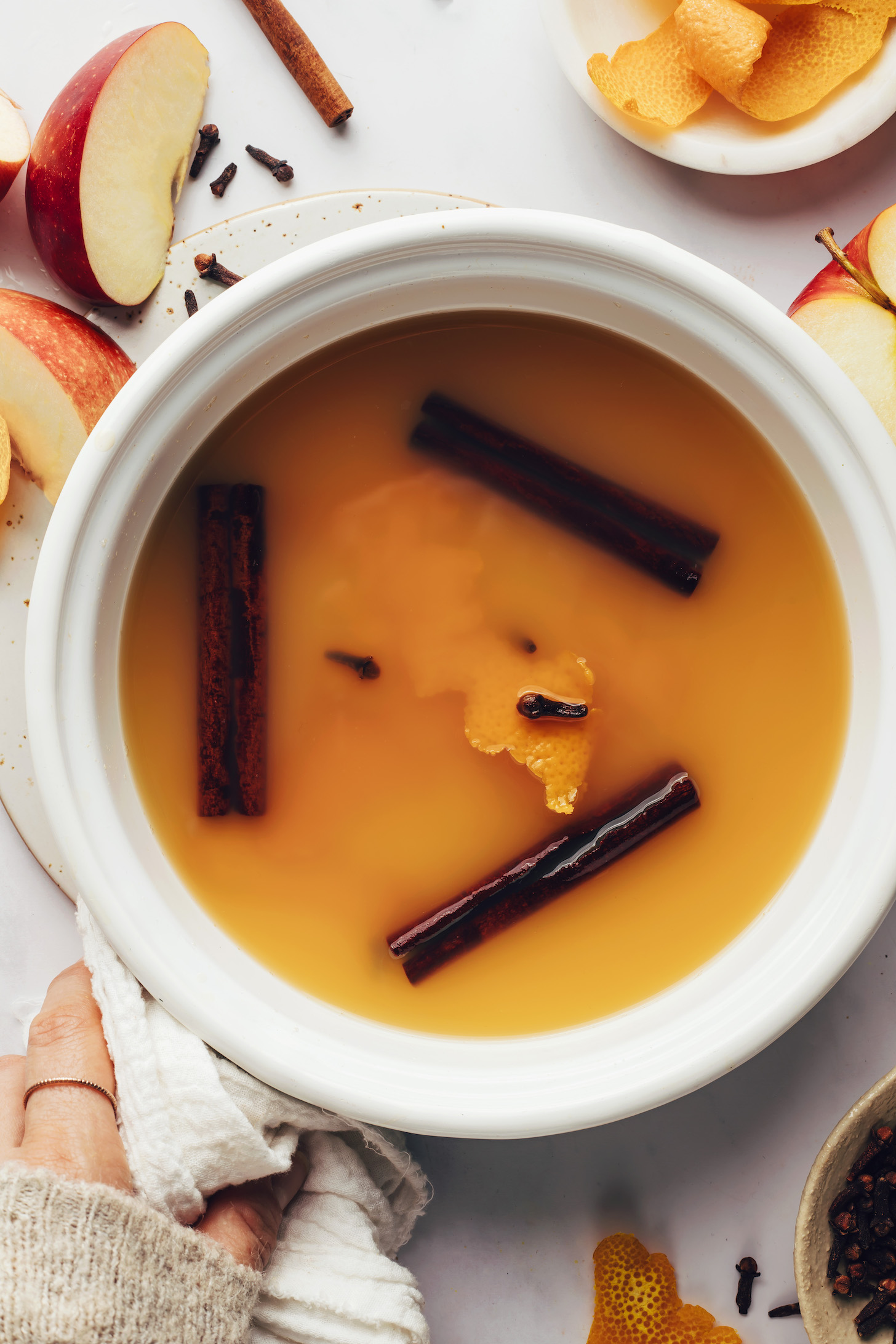 Saucepan of apple juice with cinnamon, cloves, and orange peel