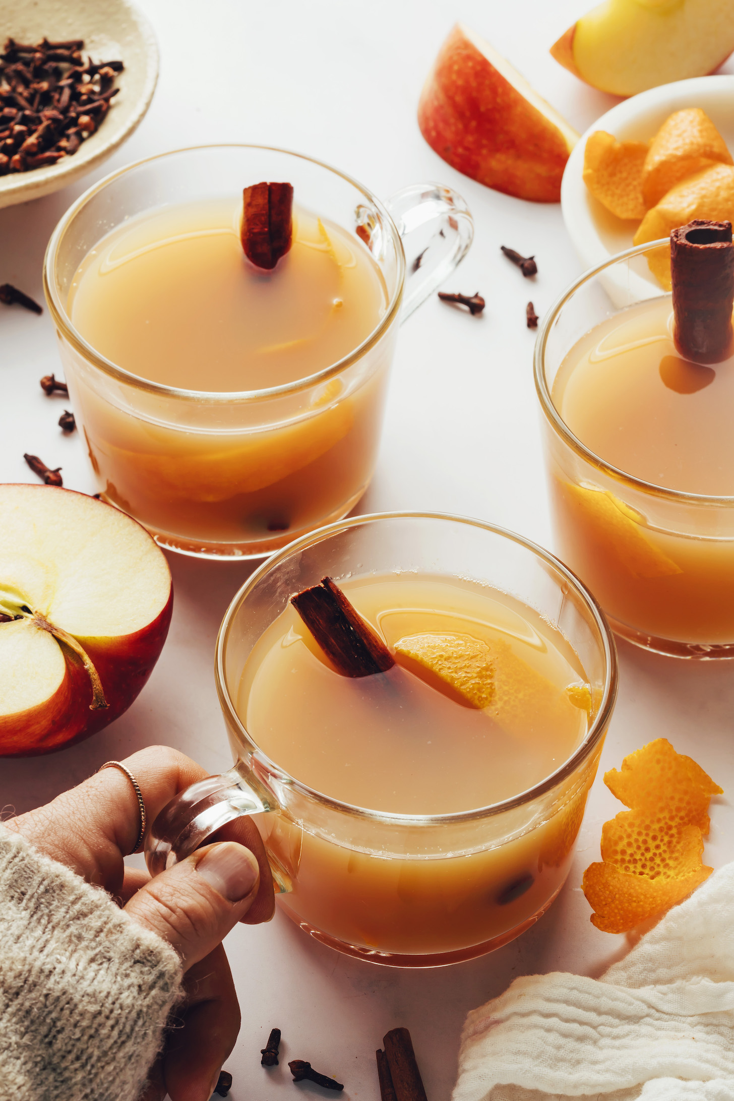 Hand holding a glass mug filled with homemade spiced apple cider