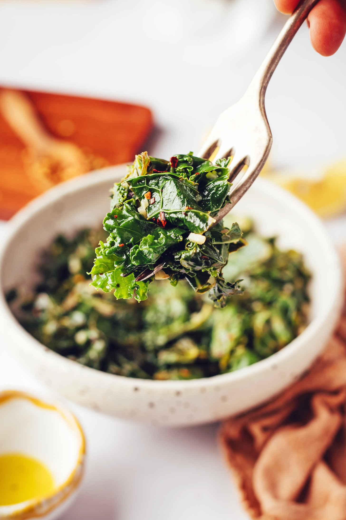 Fork spearing a bite of garlicky greens over a bowl