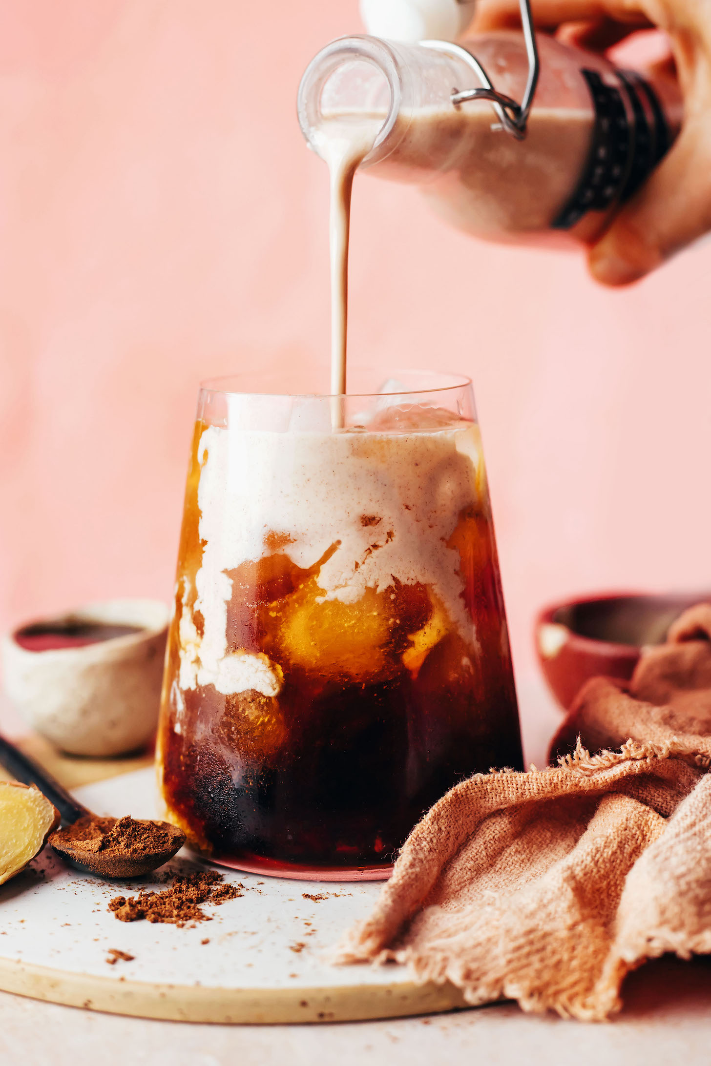 Pouring pumpkin spice coffee creamer into a glass of iced coffee