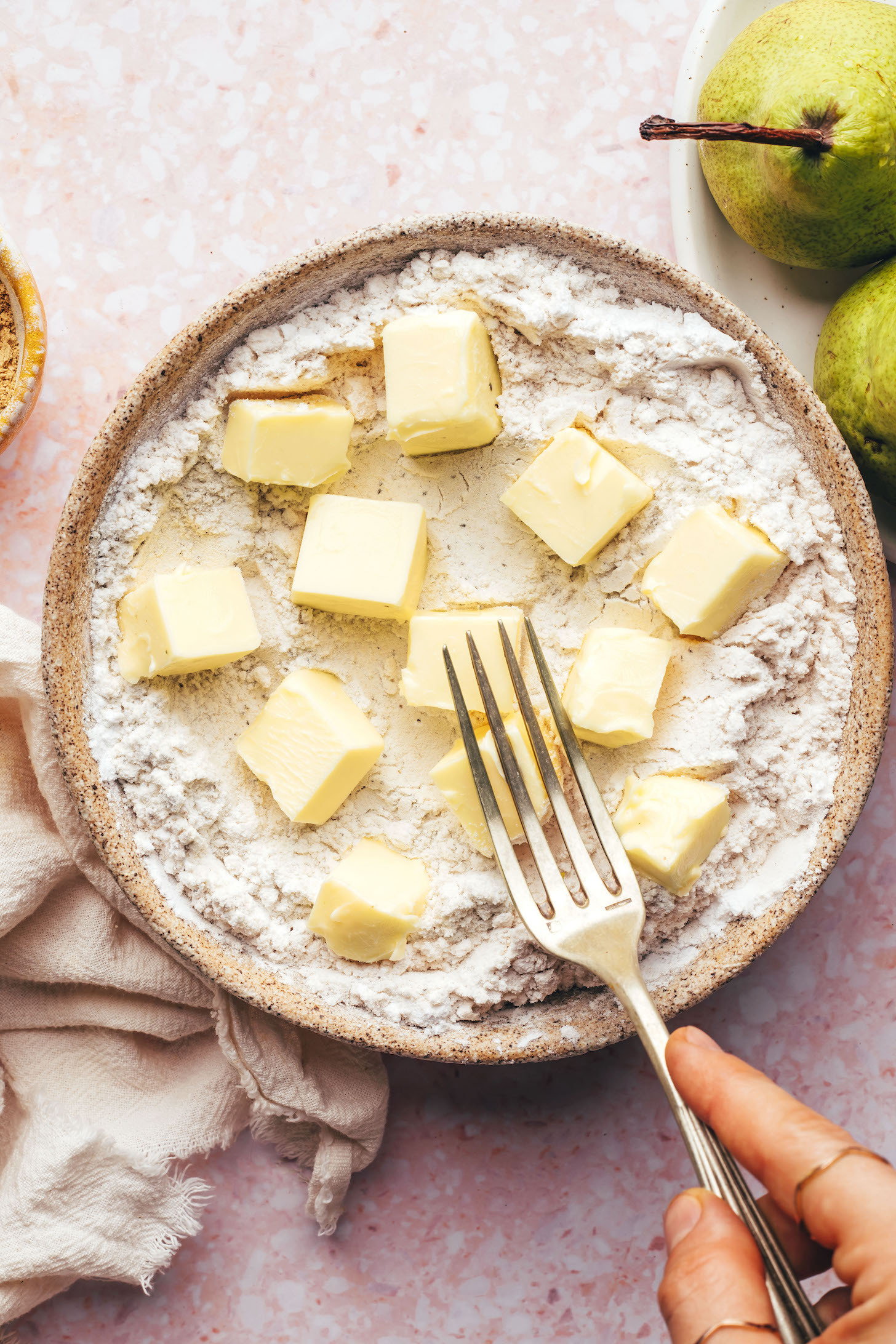 Using a fork to cut cubed vegan butter into the flours
