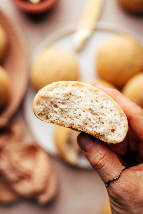 Holding up a gluten-free dinner roll to show the fluffy inner texture