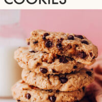Stack of vegan gluten-free cowgirl cookies next to a glass of dairy-free milk