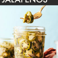 Fork holding some pickled jalapeños over a jar of more of them