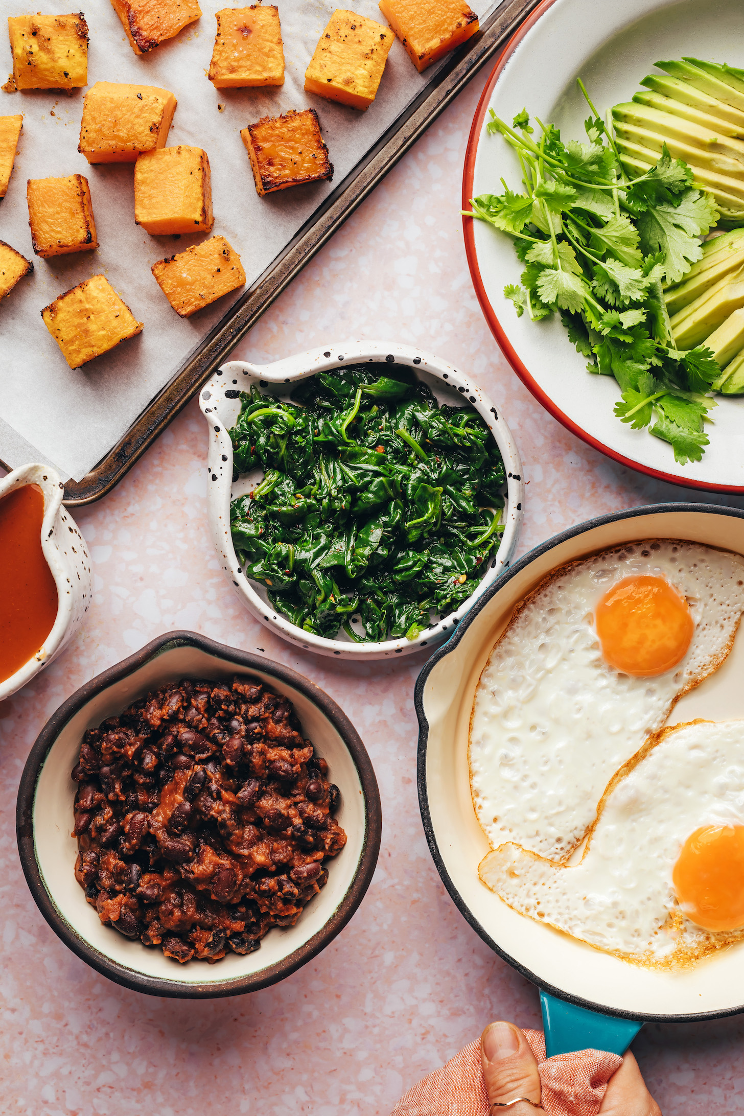 Roasted squash, sliced avocado and cilantro, fried eggs, sautéed spinach, seasoned black beans, and enchilada sauce