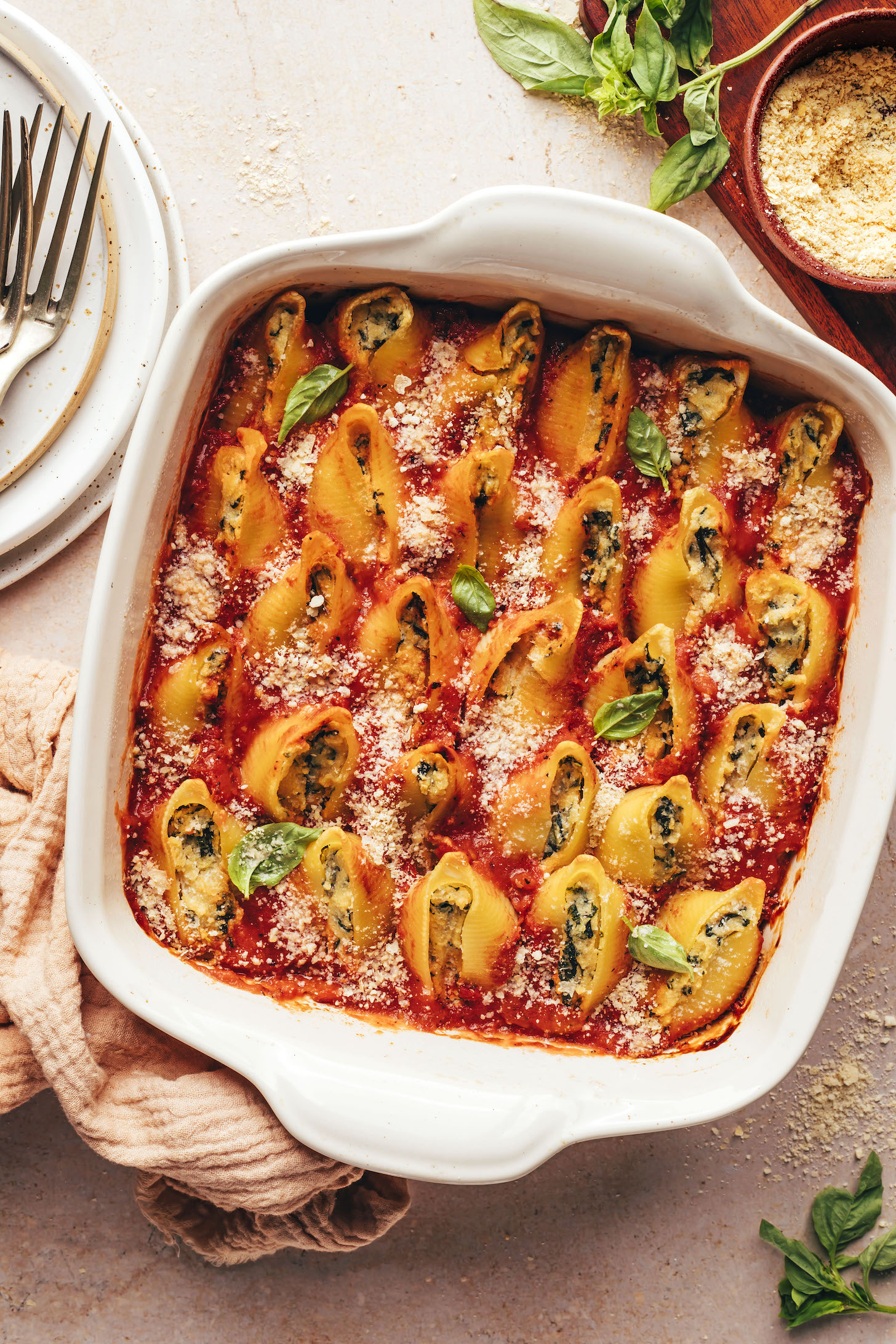 Baking dish of vegan stuffed shells sprinkled with vegan parmesan cheese and basil
