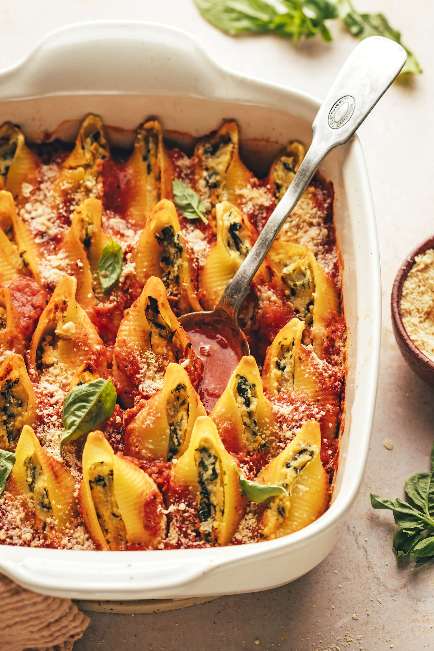 Spoon in a baking dish of vegan stuffed shells