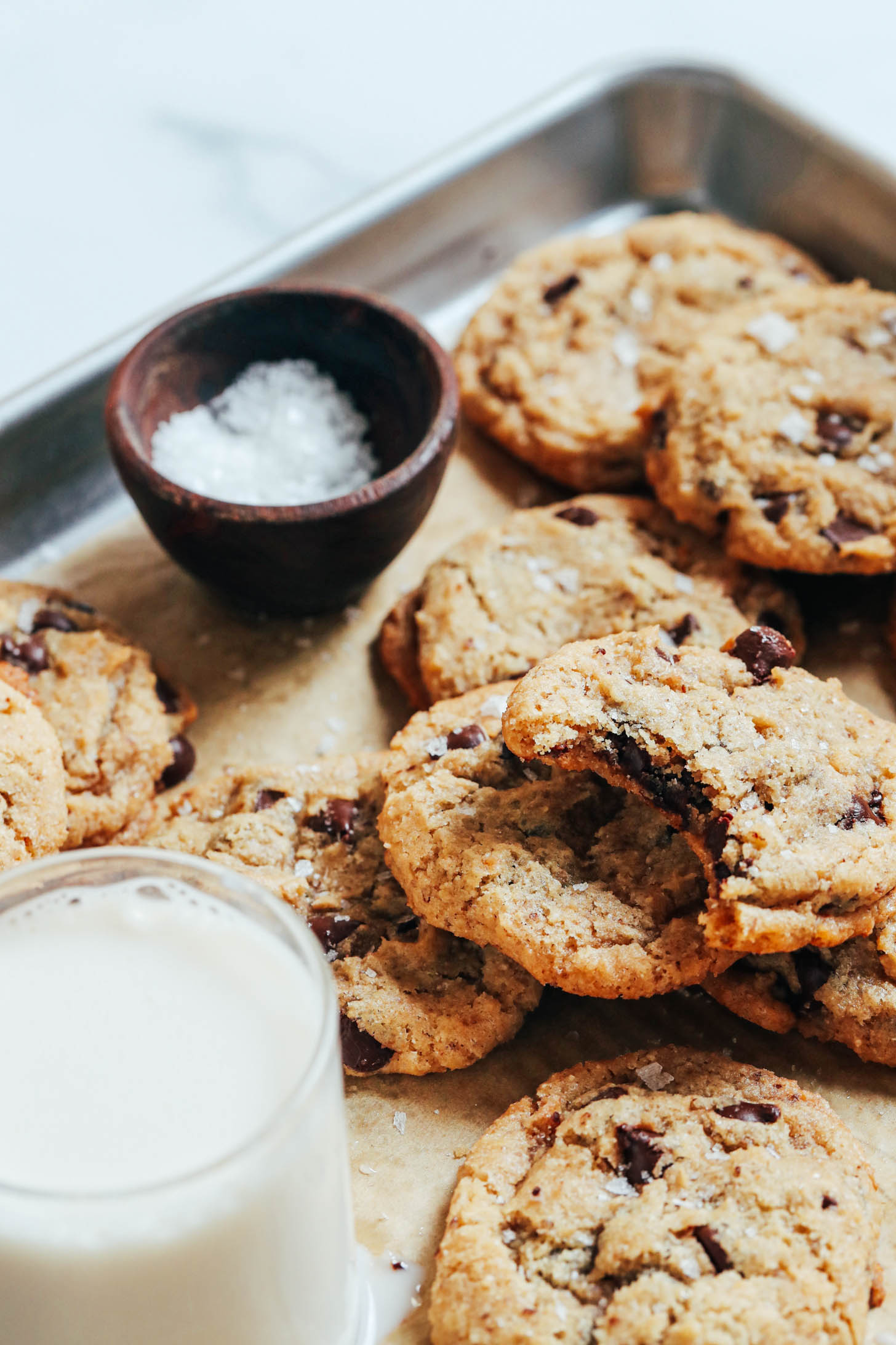 Flaky salt and dairy-free milk on a baking sheet of vegan gluten-free chocolate chip cookies