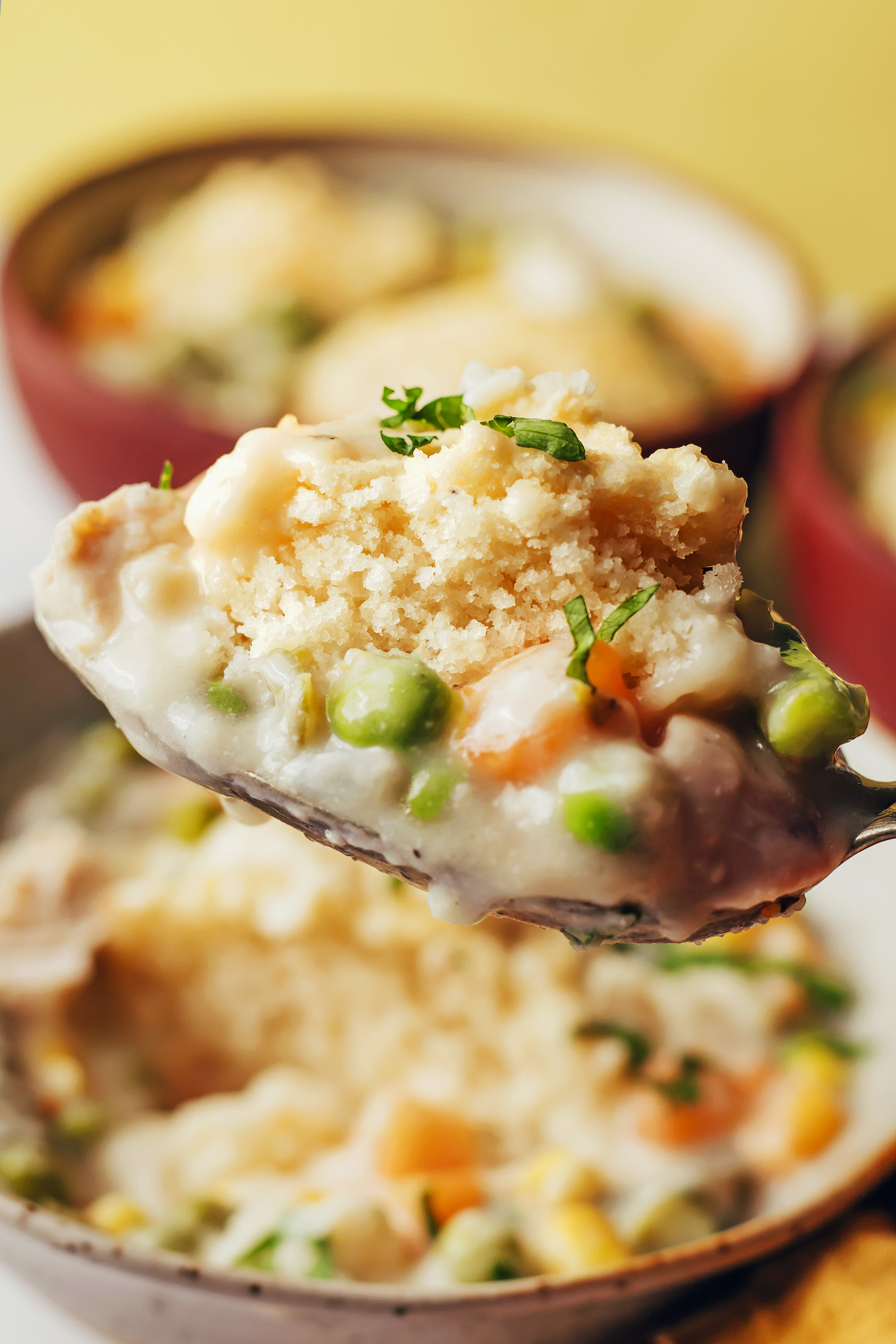 Close up shot of a spoonful of chicken pot pie soup topped with gluten-free biscuits