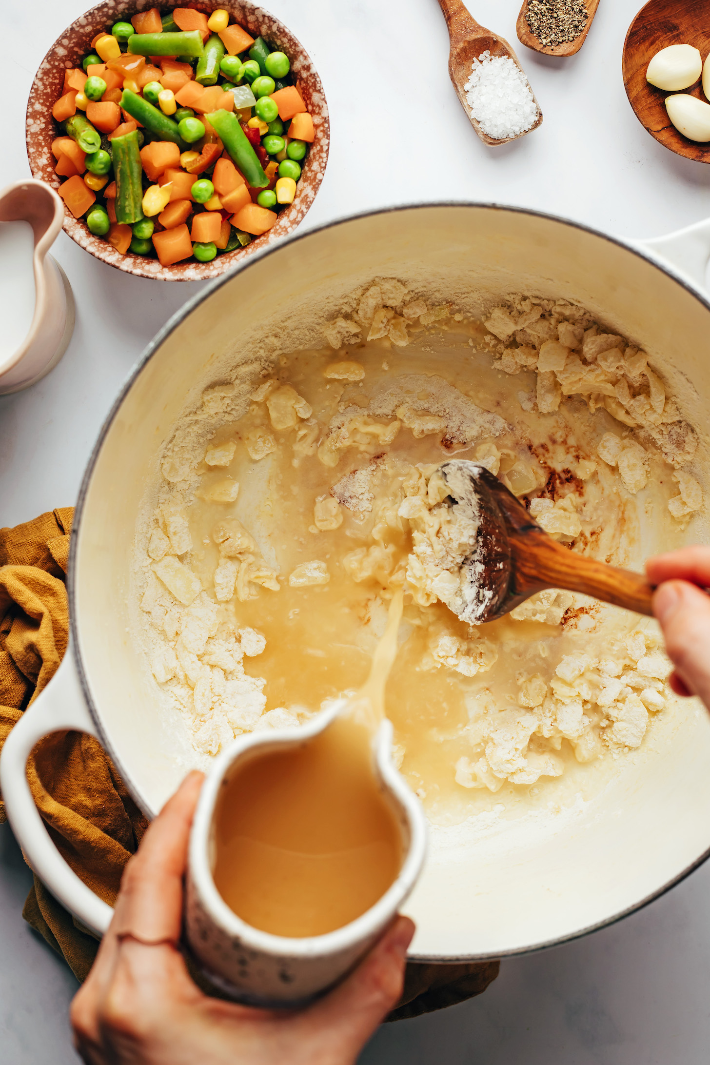 Pouring chicken broth over sautéed onions and flour
