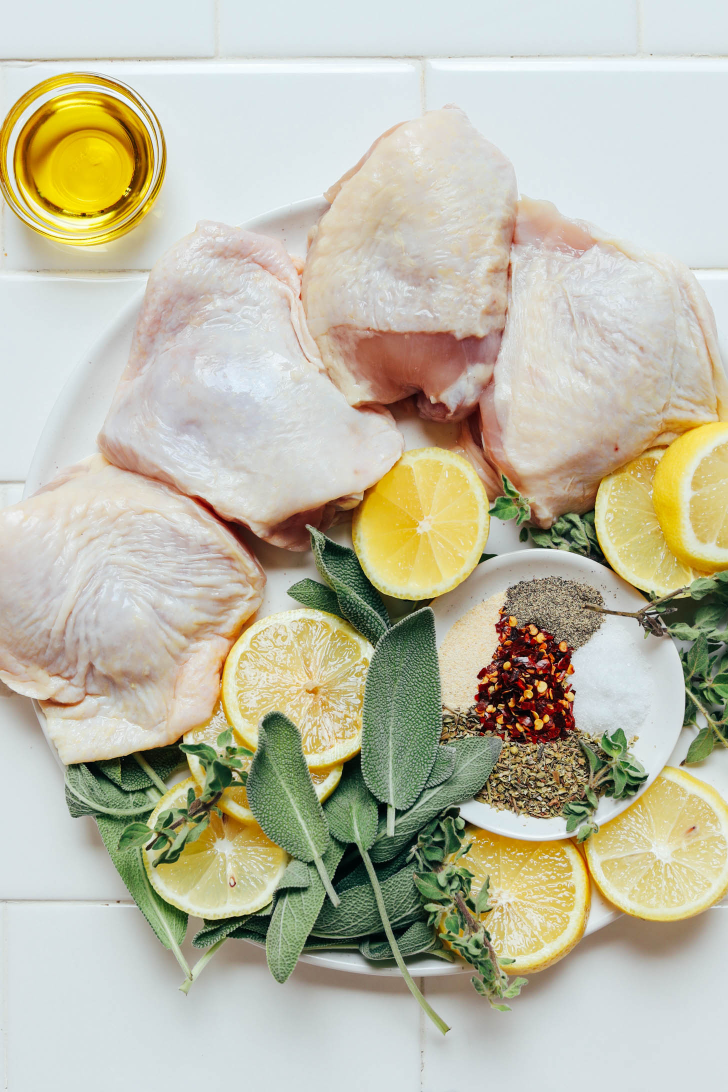 Bone-in, skin-on chicken thighs, sage, oregano, spices, lemons, and oil