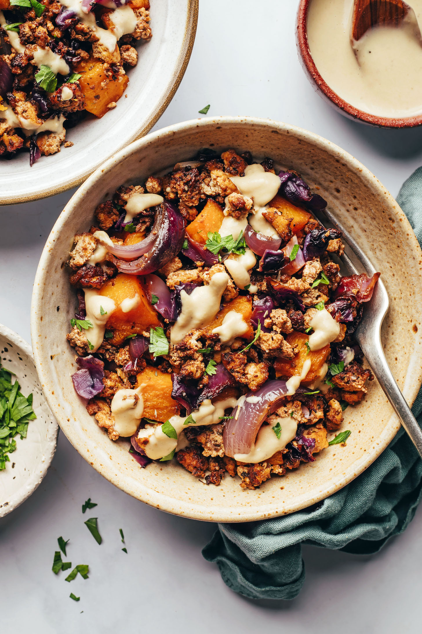 Tahini sauce drizzled over a bowl of warm roasted vegetables and Italian herb tofu