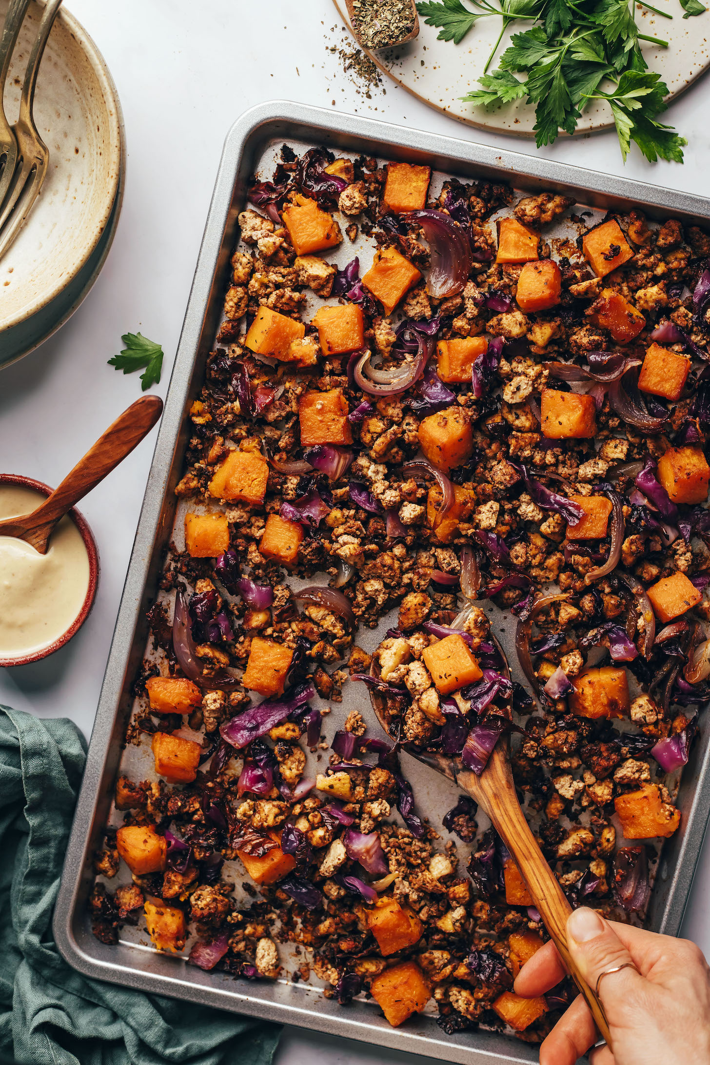 Using a wooden spoon to scoop up a serving of our roasted vegetable and tofu sheet pan dinner
