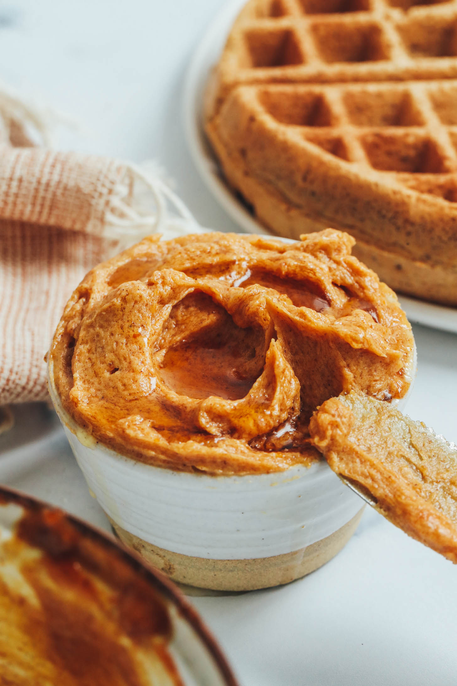 Knife resting on the side of a bowl of pumpkin-spiced maple butter