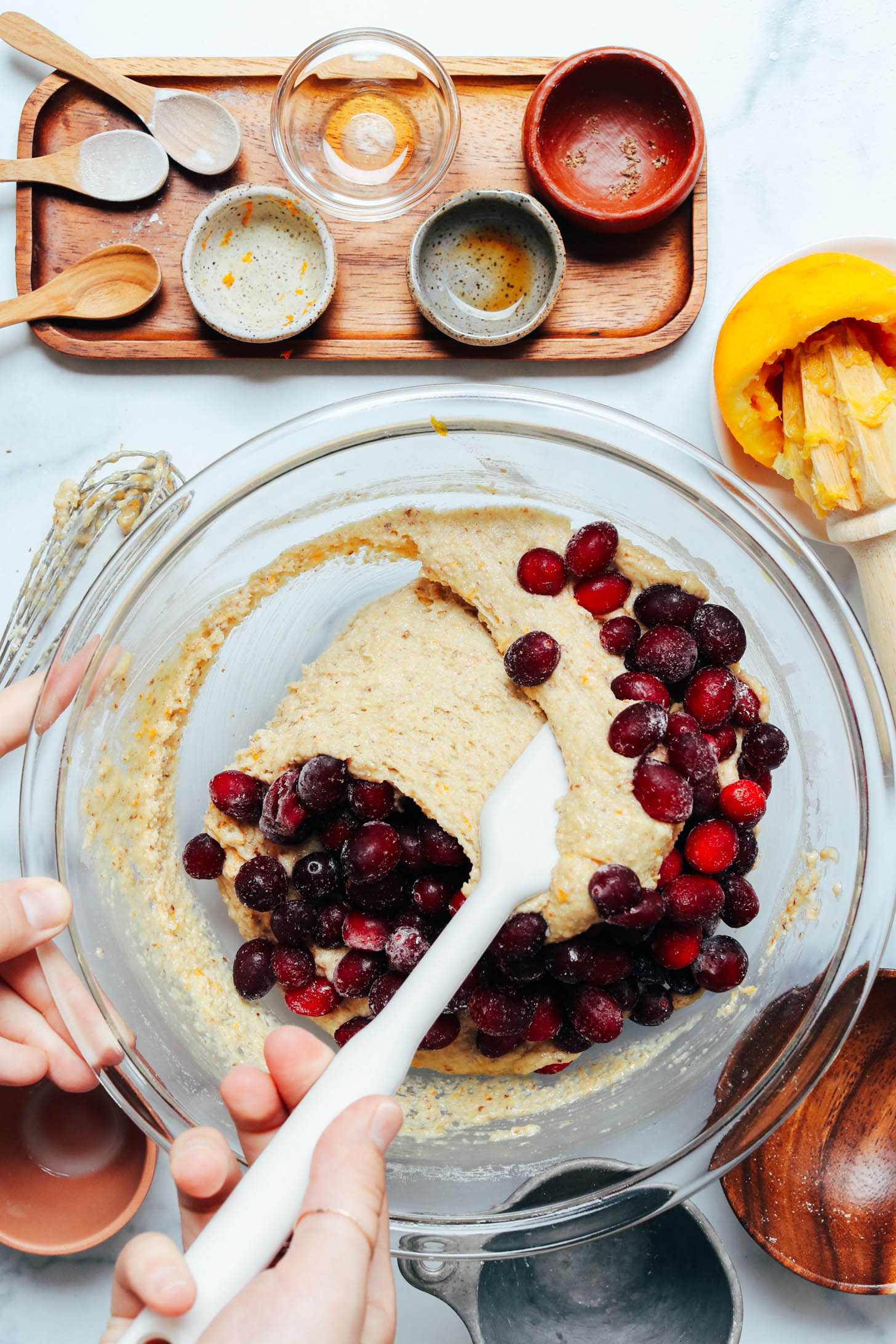 Using a rubber spatula to fold frozen cranberries into batter
