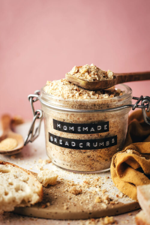 Spoonful of homemade breadcrumbs resting on a labeled jar