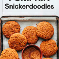 Bowl of cinnamon sugar on a baking sheet with vegan gluten-free pumpkin snickerdoodles