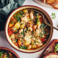 Bowl of vegetable and bean soup topped with vegan parmesan cheese