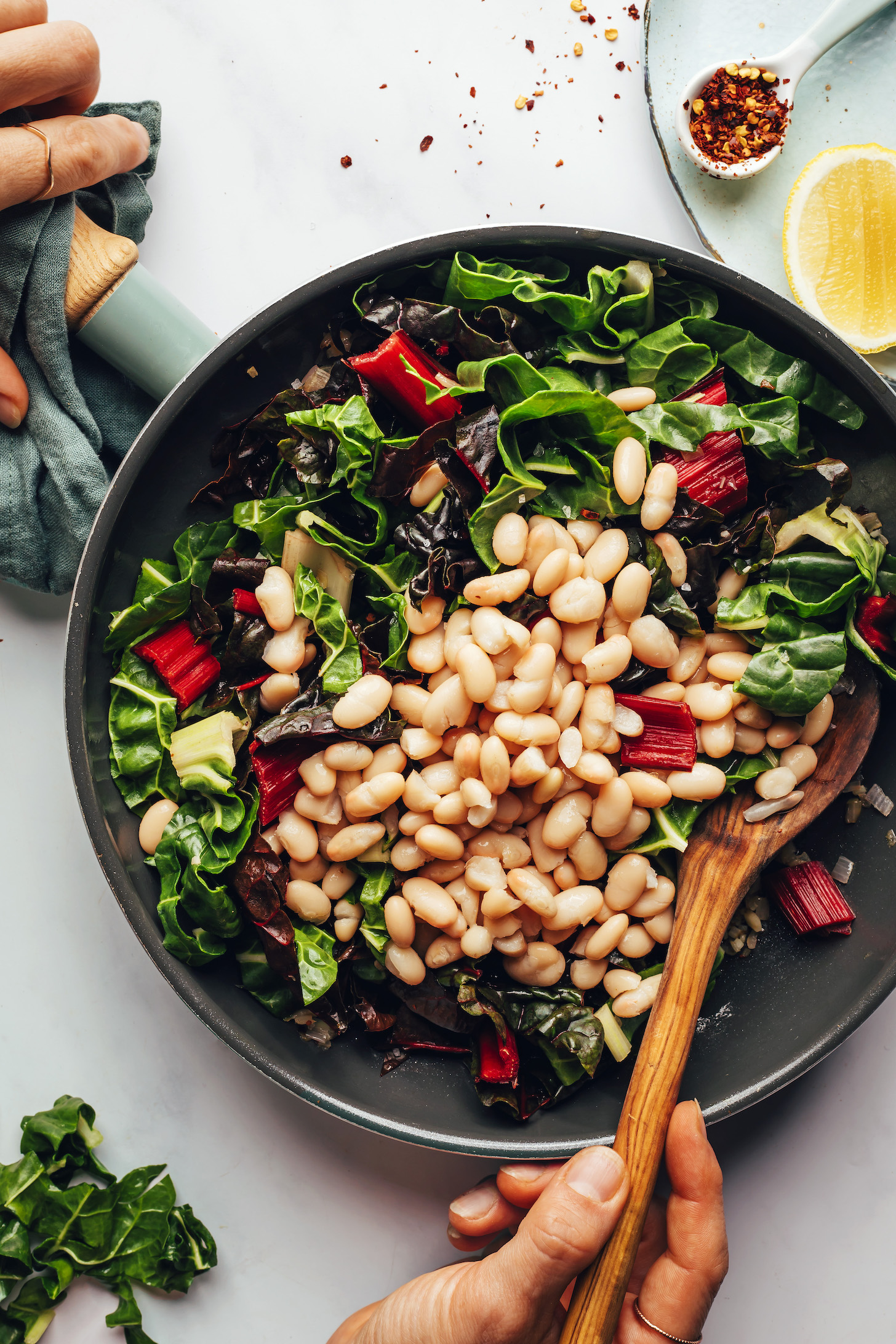Stirring white beans and chard in a skillet