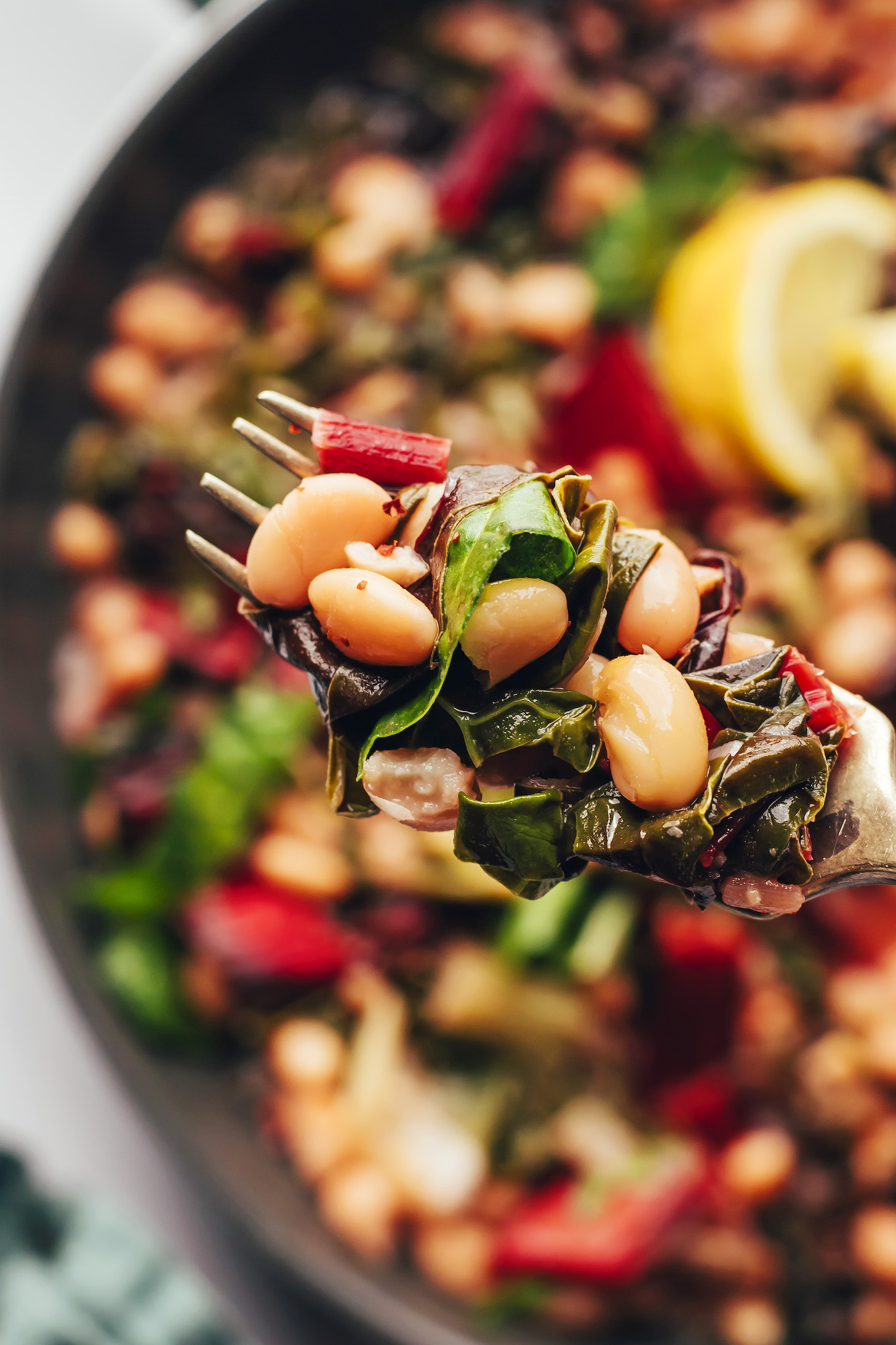 Fork holding up a bite of sautéed beans and greens