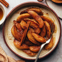 Cinnamon stick over a plate of caramelized cinnamon-spiced pears