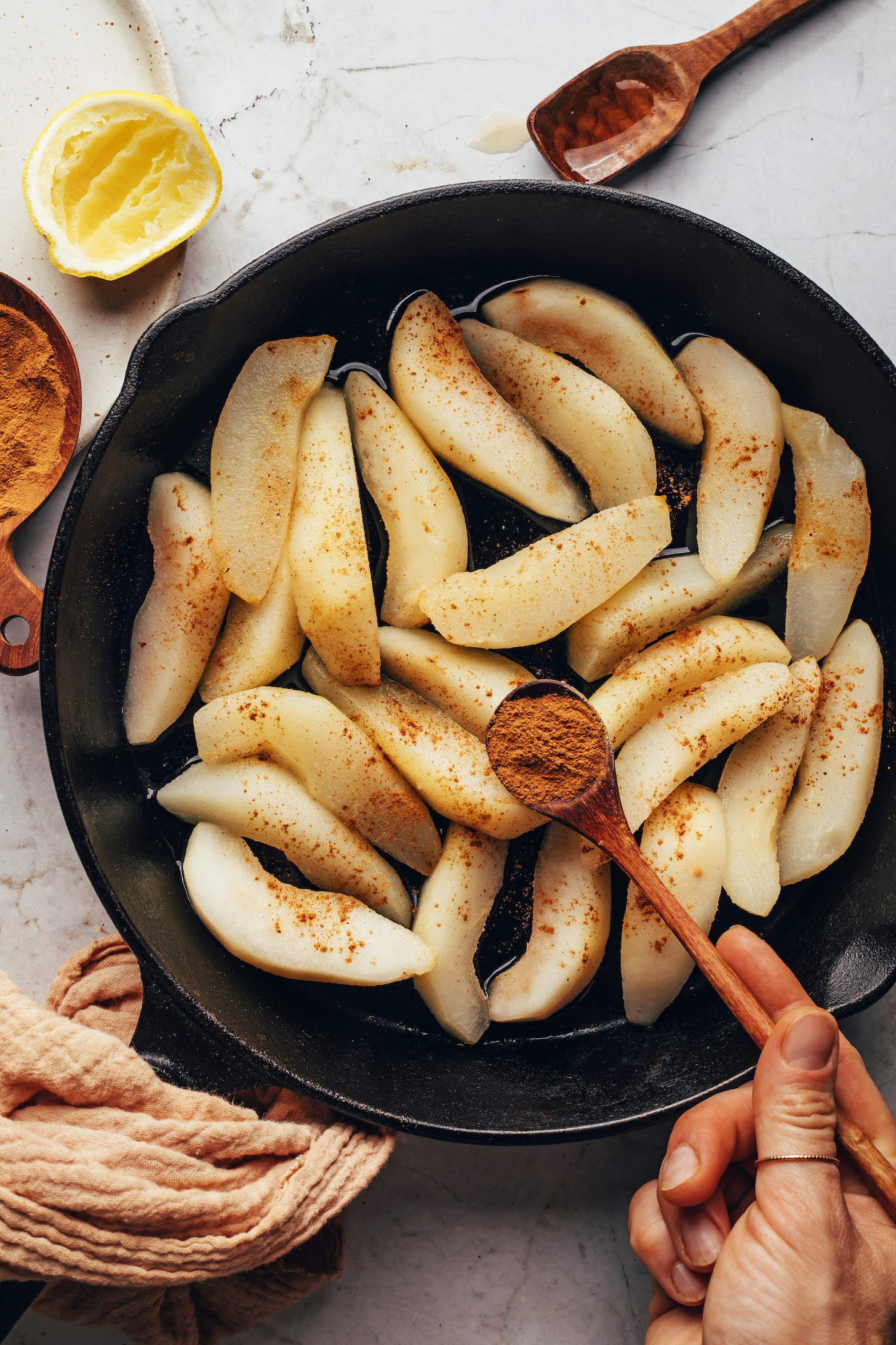 Sprinkling ground cinnamon onto sliced pears