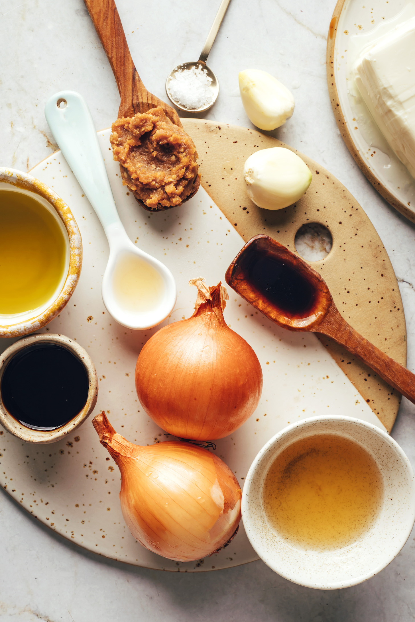 Olive oil, lemon juice, miso paste, salt, garlic cloves, maple syrup, onions, vinegar, and tamari