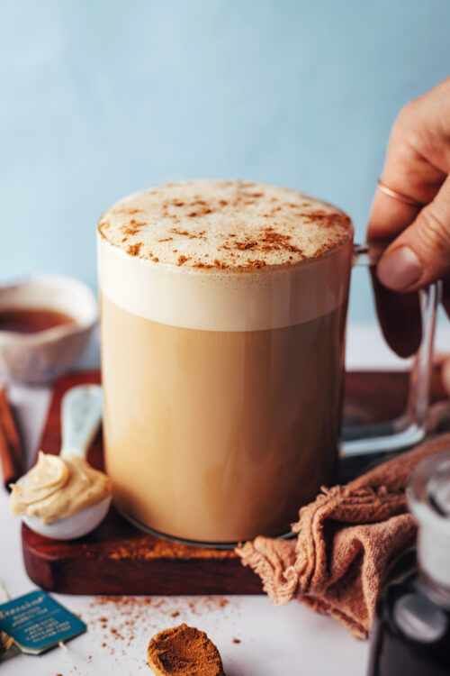 Holding the handle of a glass mug filled with our dandelion tea latte recipe