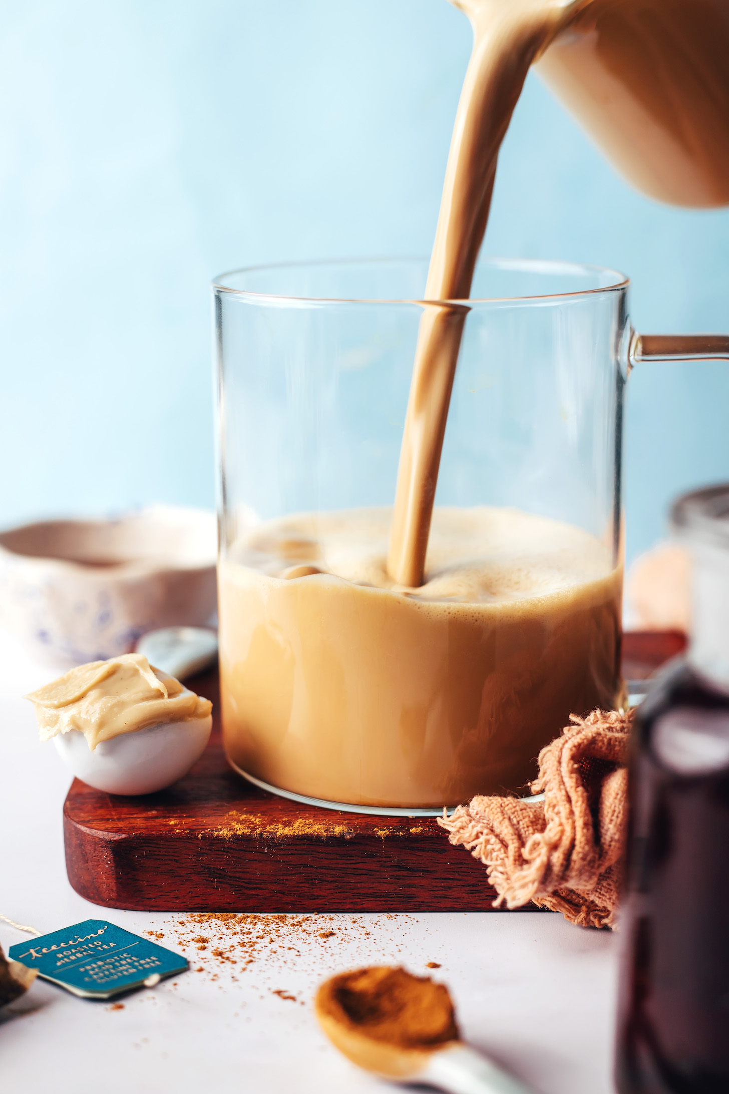 Pouring a cinnamon vanilla dandelion latte into a glass mug