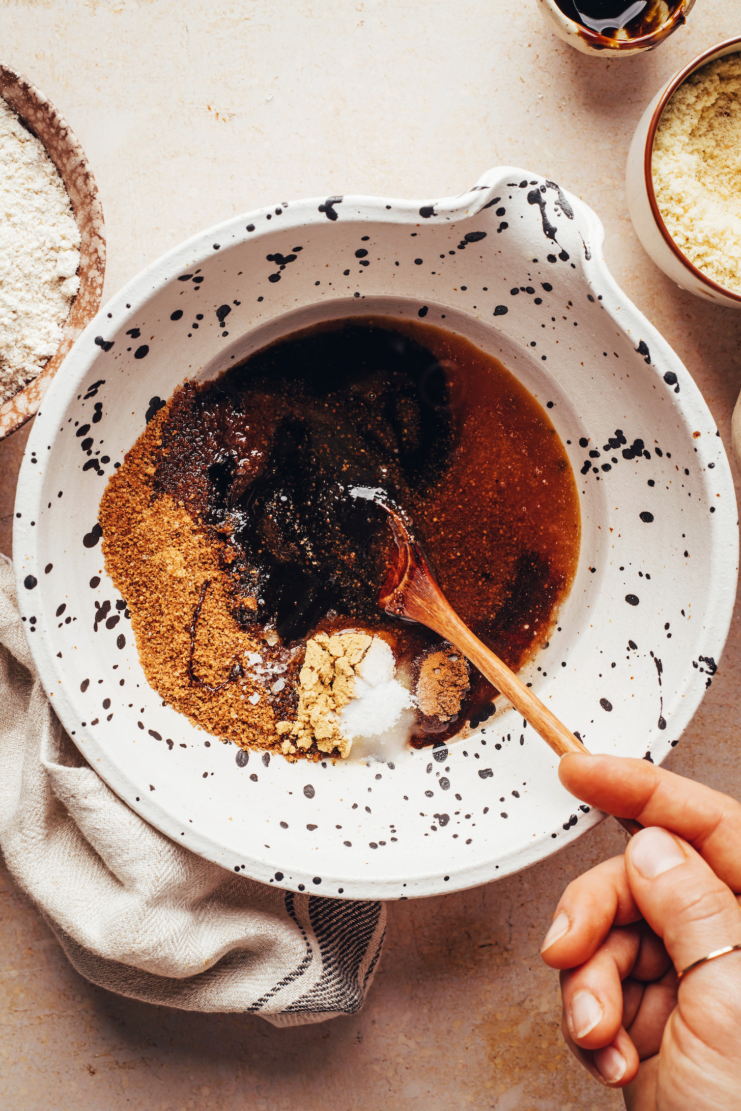 Stirring maple syrup, coconut sugar, coconut oil, molasses, and spices in a bowl