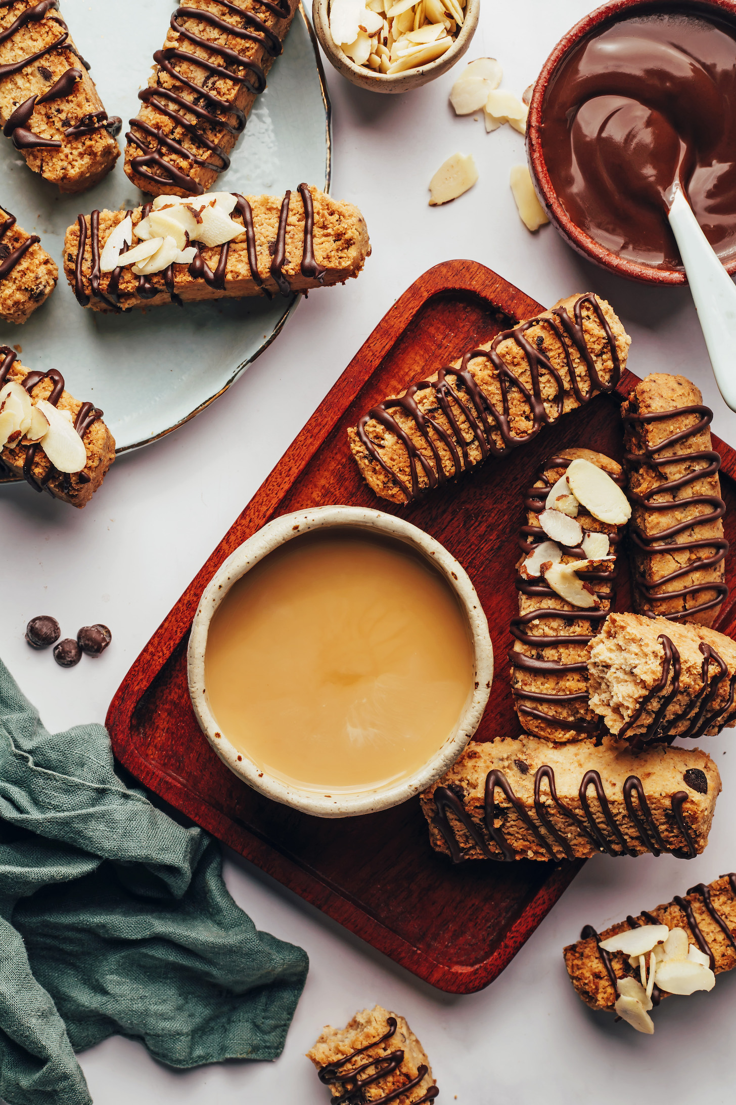 Mug of coffee next to gluten-free almond biscotti drizzled with melted chocolate