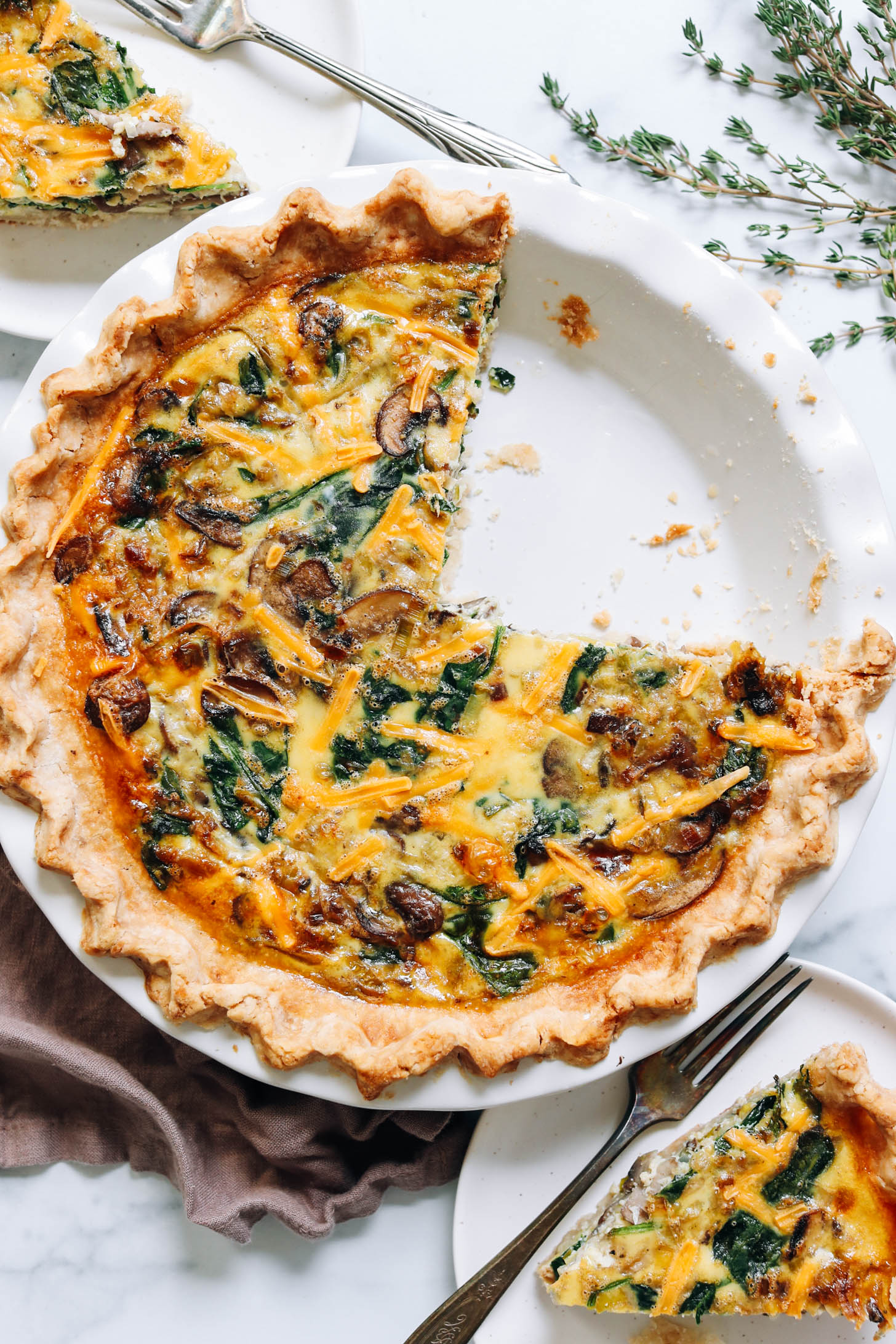Pie pan filled with a gluten-free dairy-free quiche with a couple slices removed