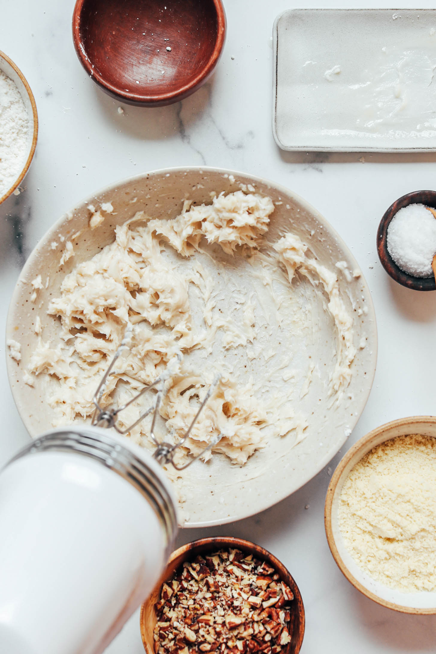 Using a hand mixer to whip vegan butter and powdered sugar in a bowl