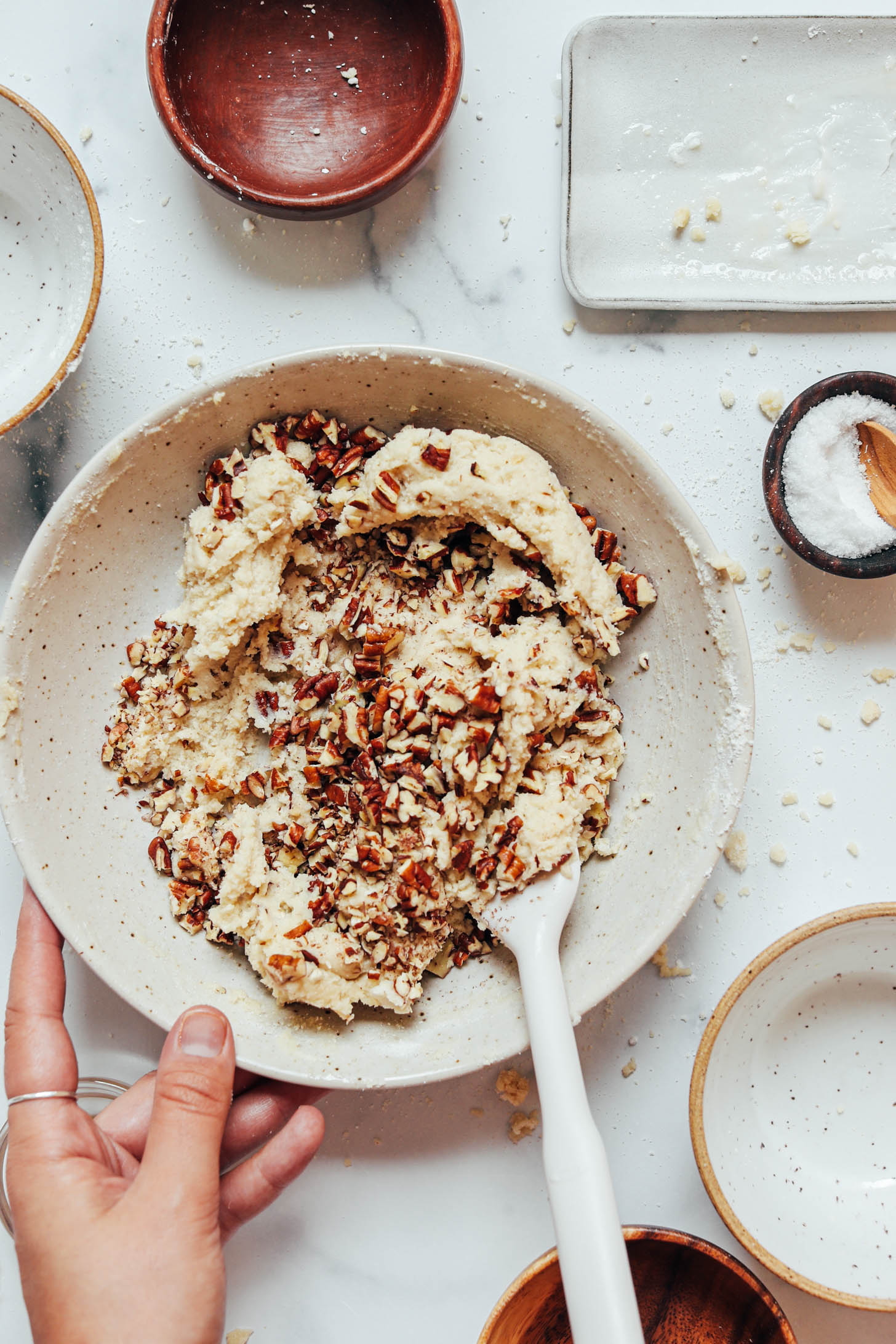 Stirring chopped pecans into vegan gluten-free Mexican wedding cookie dough