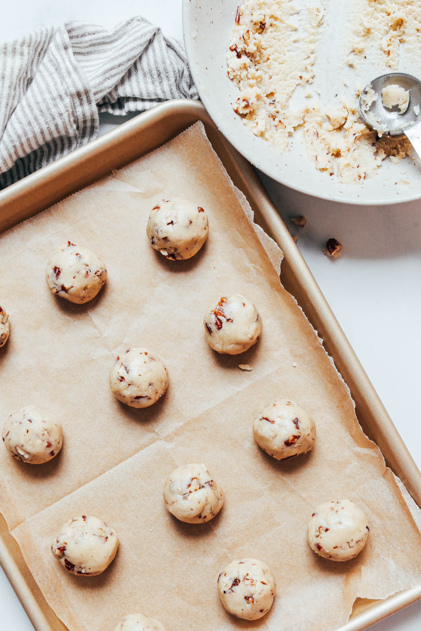 Balls of Mexican wedding cookie dough on a parchment-lined baking sheet