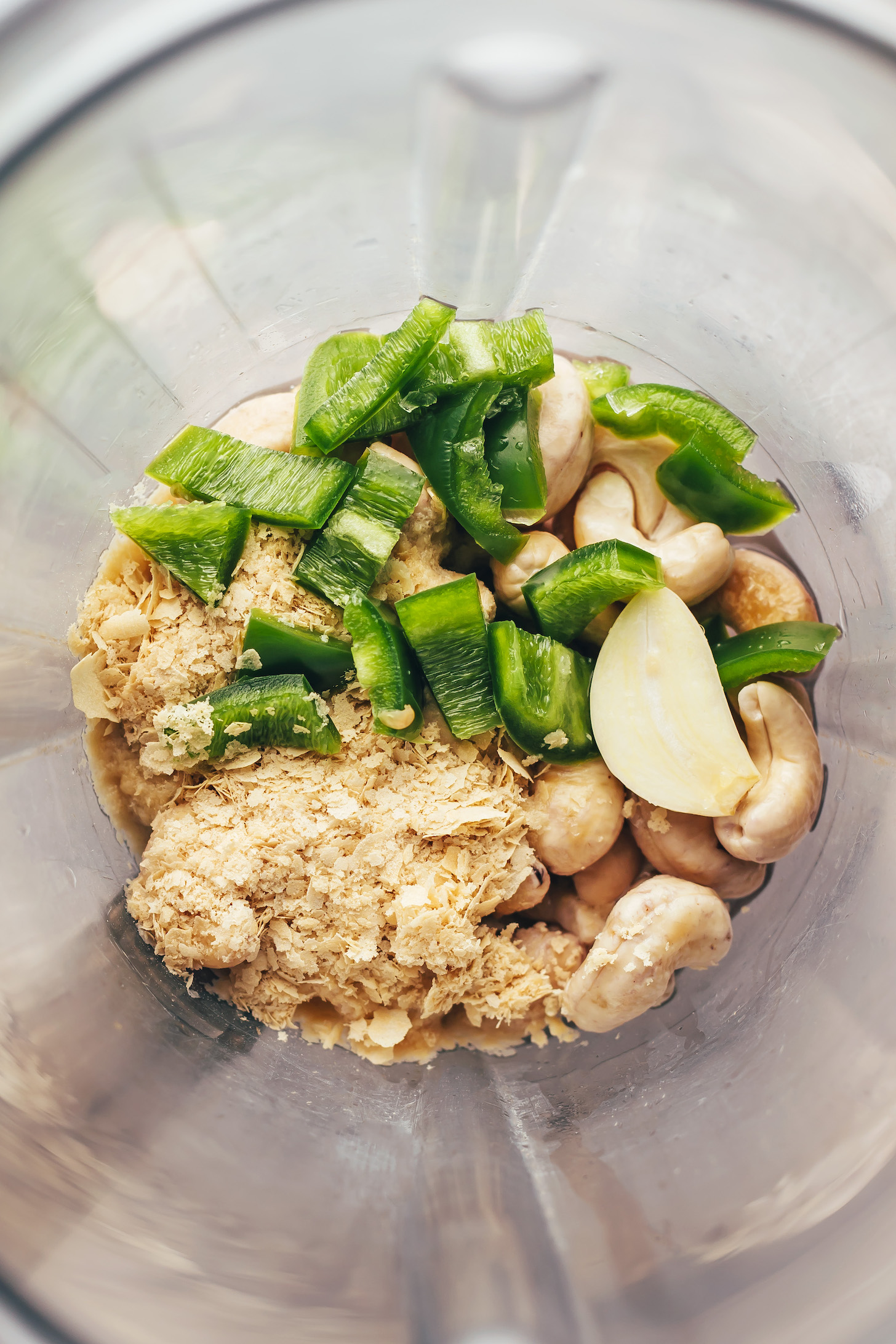 Blender with cashews, nutritional yeast, jalapeño, garlic, lime juice, and salt