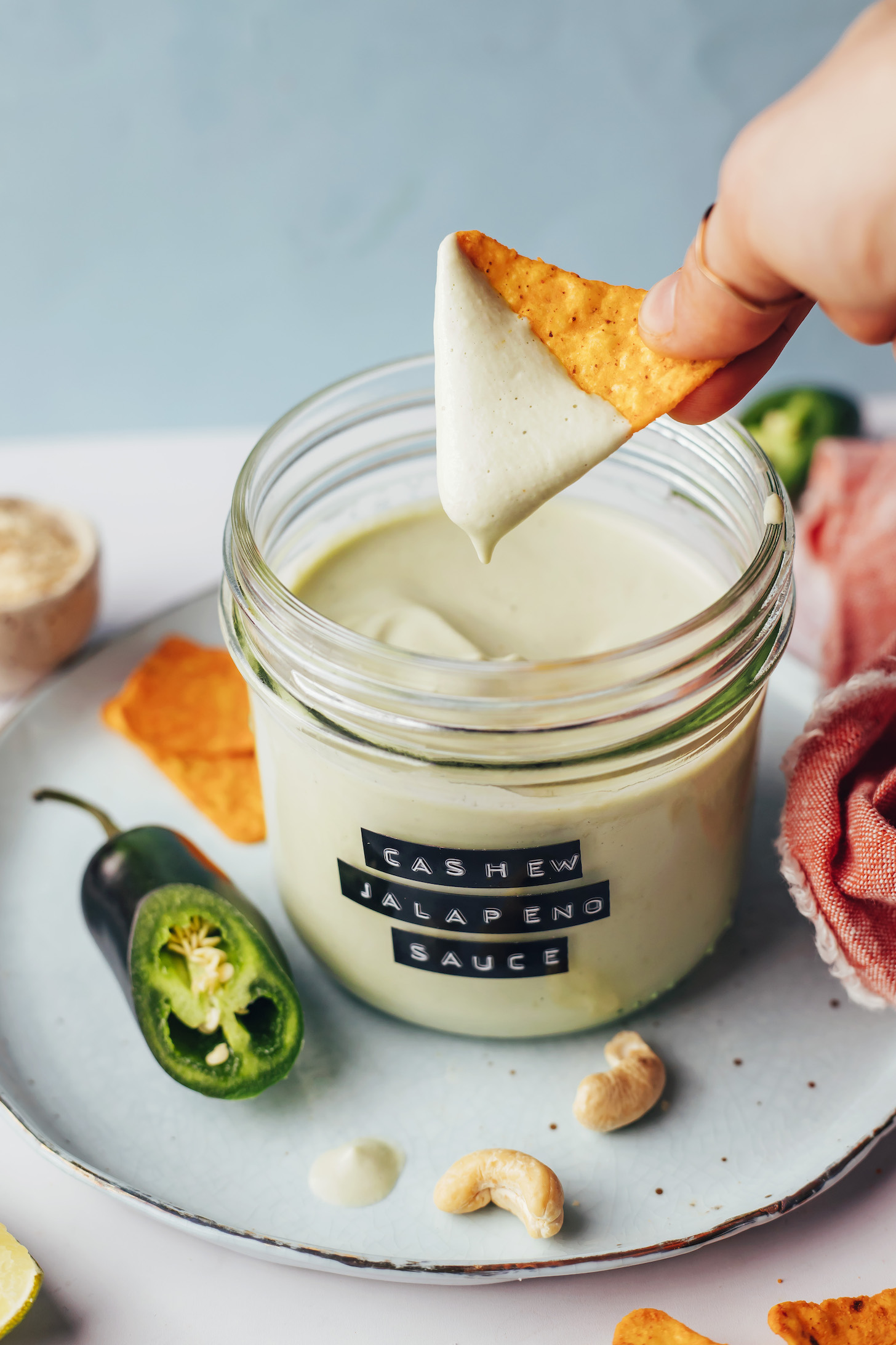 Holding a tortilla chip coated with cashew jalapeño sauce over a jar