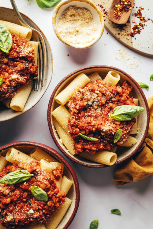 Bowls of vegan lentil bolognese topped with fresh basil