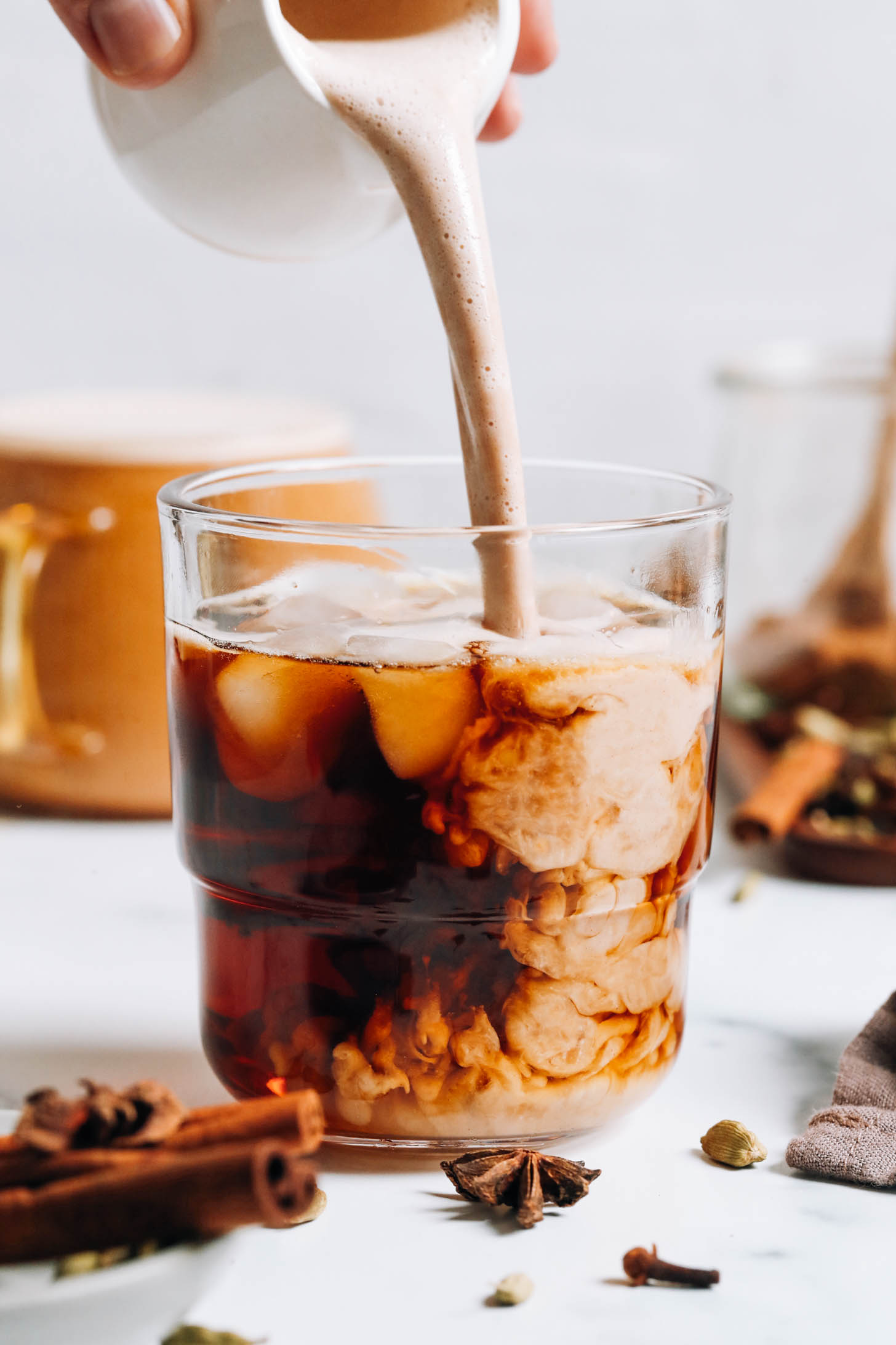 Pouring chai-spiced coffee creamer into coffee to make a dirty chai
