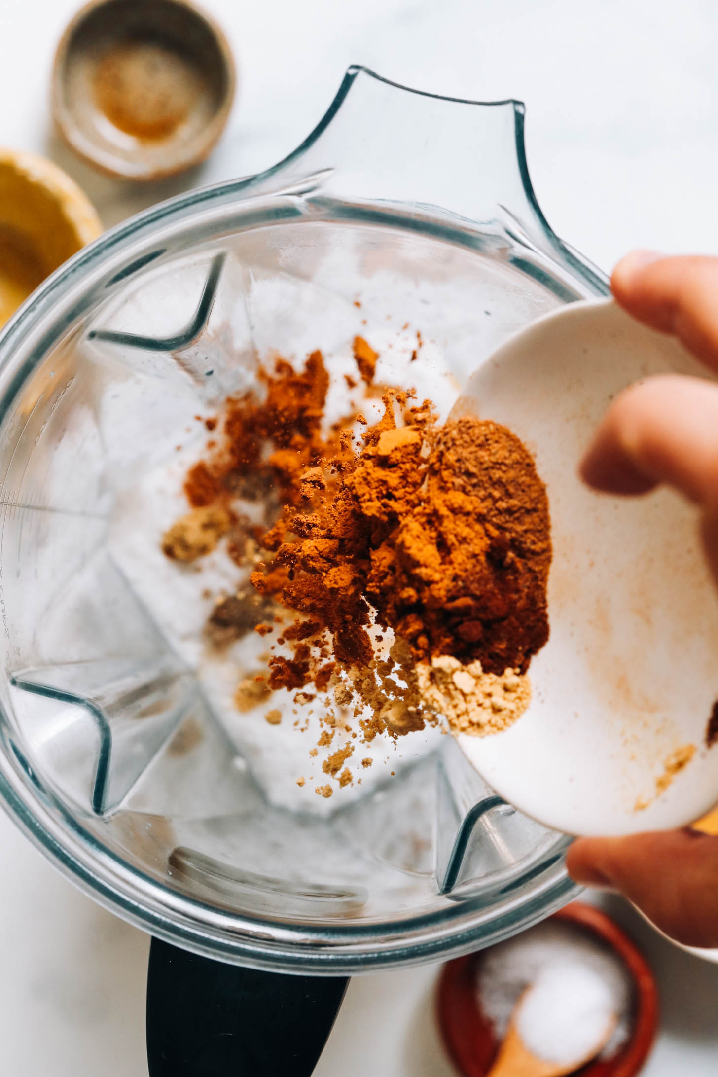 Adding cinnamon, ginger, cardamom, cloves, nutmeg, and salt to a blender