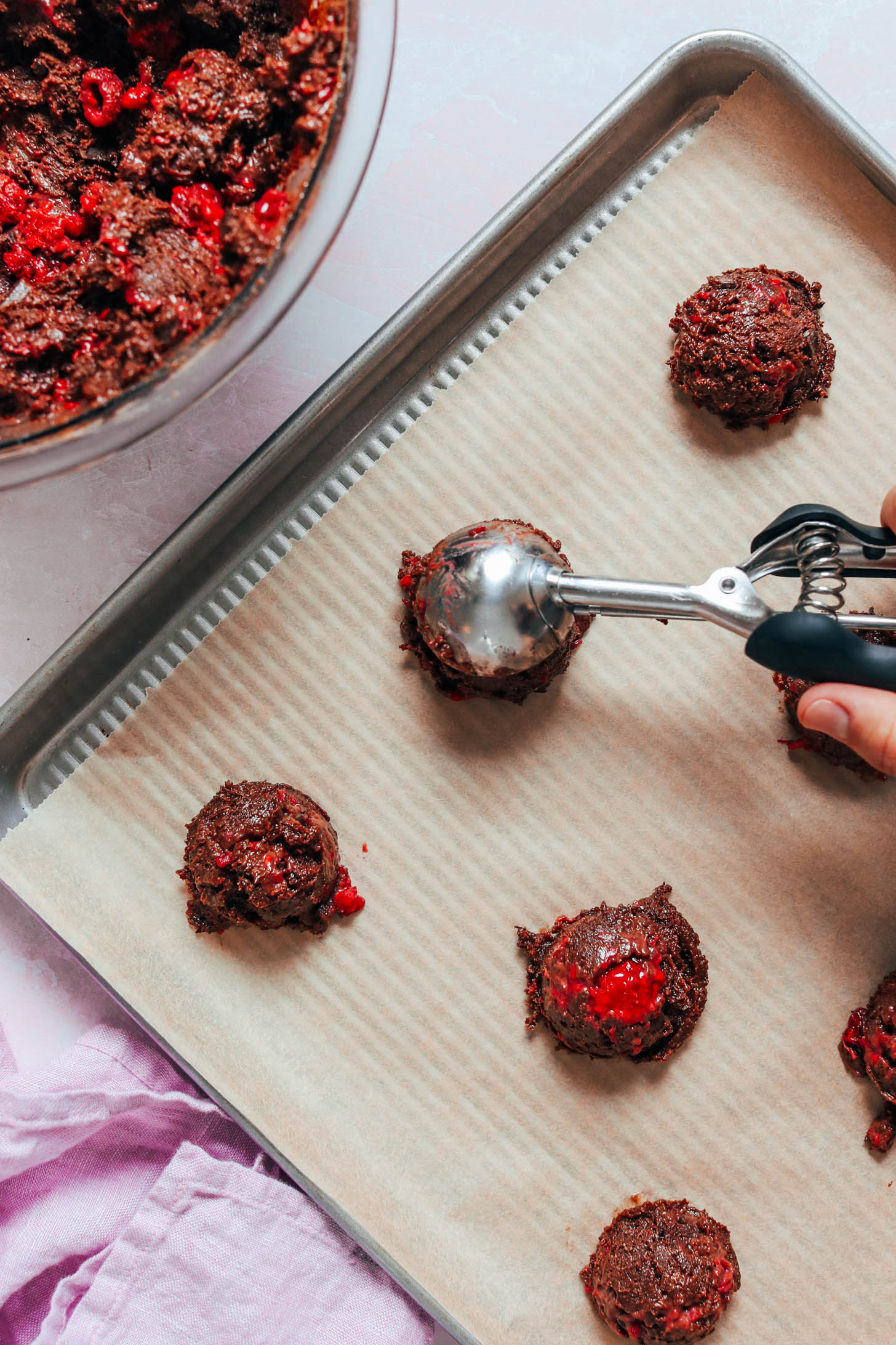 Scooping chocolate cake mix cookie batter onto a baking sheet