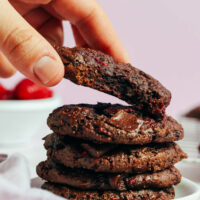 Placing a gluten-free chocolate cake mix cookie onto a stack of more cookies